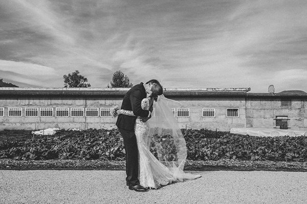 Black and white image of newlyweds kissing in a garden